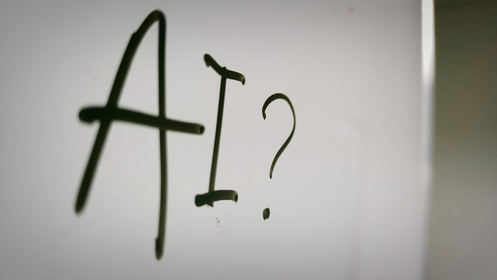 The letters AI followed by a question mark, handwritten on a whiteboard